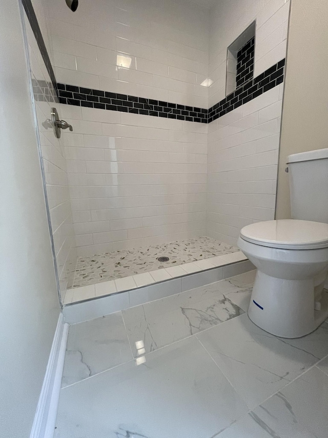 bathroom featuring a tile shower and toilet