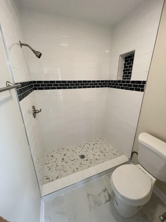 bathroom featuring a tile shower and toilet