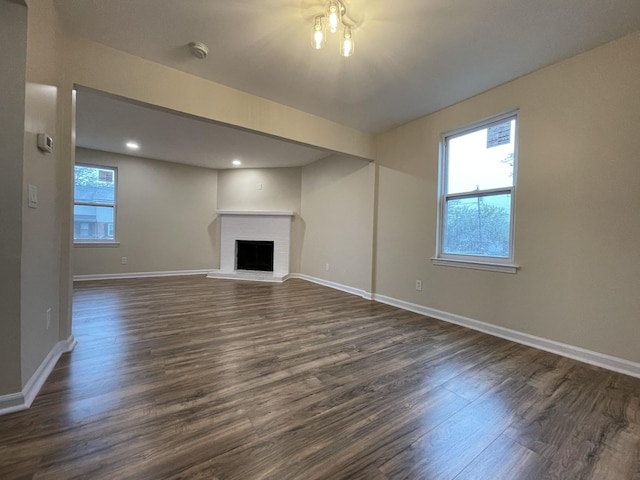 unfurnished living room with a fireplace, plenty of natural light, and dark wood-type flooring