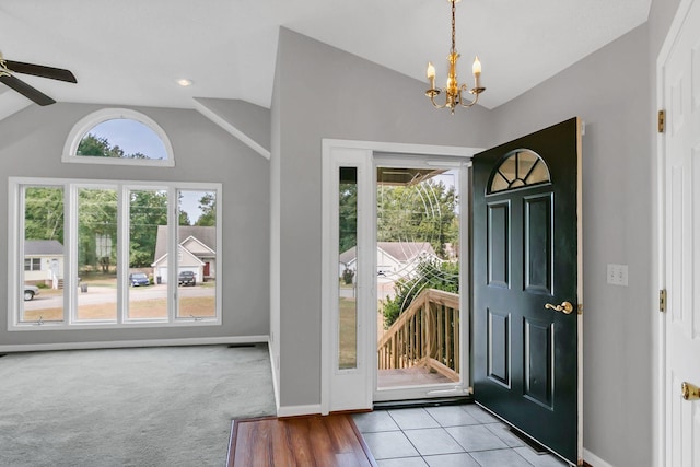 carpeted entrance foyer with ceiling fan with notable chandelier and lofted ceiling