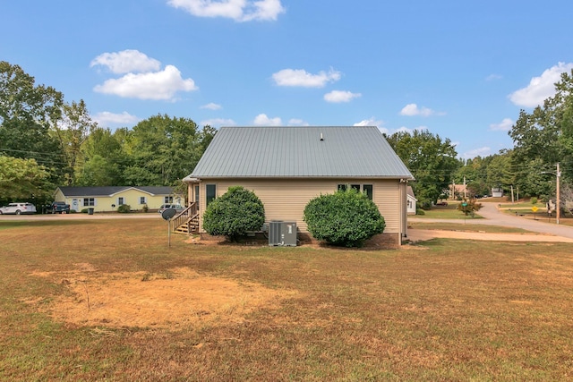 view of side of home with central AC and a lawn