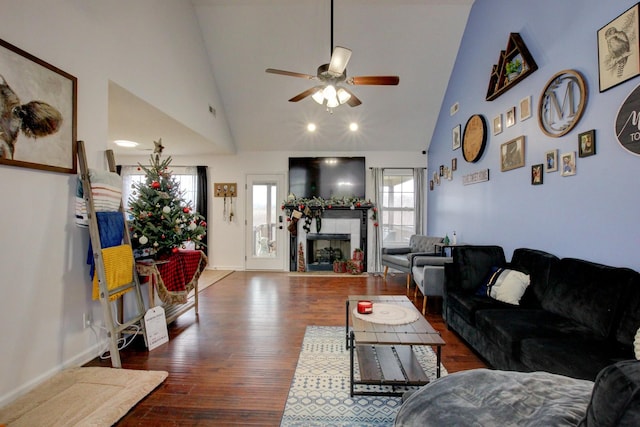 living room featuring ceiling fan, dark wood-type flooring, high vaulted ceiling, and a tiled fireplace