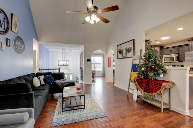 living room featuring dark hardwood / wood-style floors, ceiling fan with notable chandelier, and high vaulted ceiling