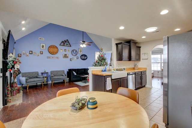 dining space with ceiling fan, sink, light hardwood / wood-style floors, and vaulted ceiling