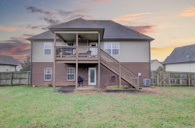 back house at dusk with a lawn, ceiling fan, a wooden deck, cooling unit, and a patio area