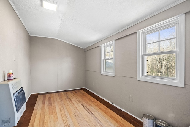 bonus room featuring a textured ceiling, heating unit, vaulted ceiling, and hardwood / wood-style flooring