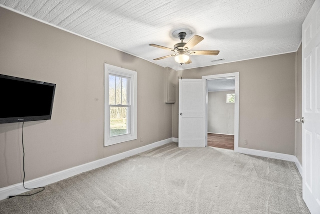 unfurnished bedroom with ceiling fan, light colored carpet, and a textured ceiling