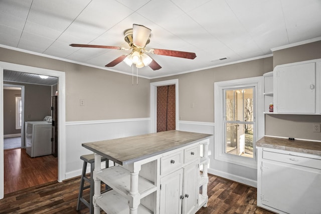 kitchen featuring dark hardwood / wood-style flooring, washing machine and dryer, and white cabinetry