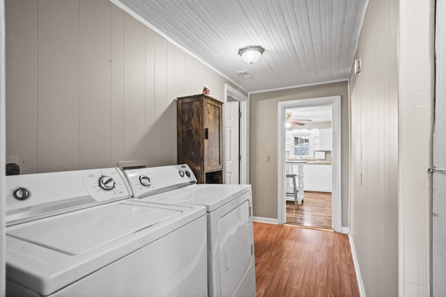 laundry area featuring hardwood / wood-style floors, crown molding, wooden walls, ceiling fan, and washing machine and dryer