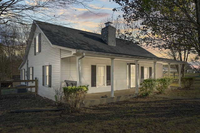 property exterior at dusk featuring covered porch