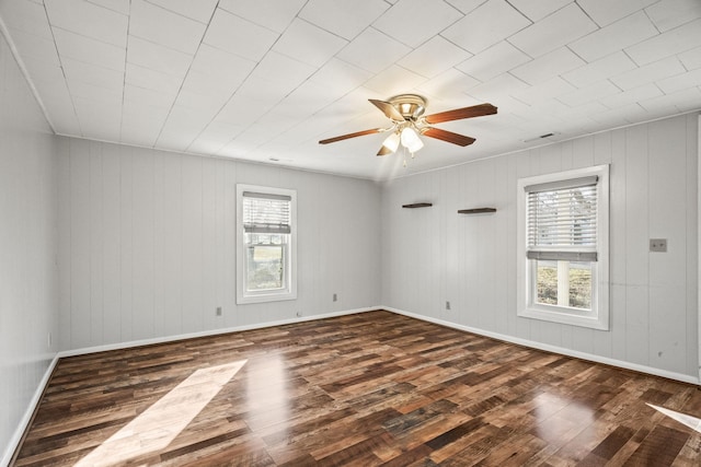 unfurnished room featuring dark hardwood / wood-style floors, ceiling fan, and wooden walls