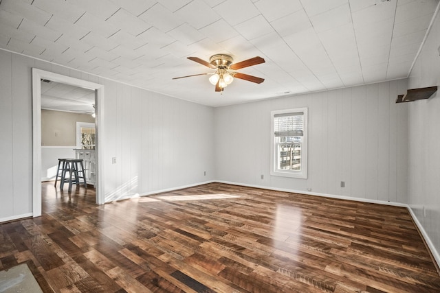 spare room featuring dark hardwood / wood-style flooring, ceiling fan, and wooden walls