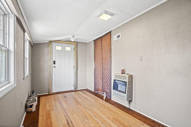 foyer featuring hardwood / wood-style flooring, heating unit, crown molding, and vaulted ceiling