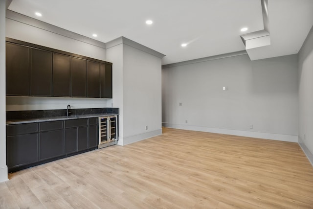 bar featuring wine cooler, crown molding, sink, and light wood-type flooring