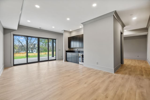 unfurnished living room featuring crown molding, sink, beverage cooler, and light hardwood / wood-style floors