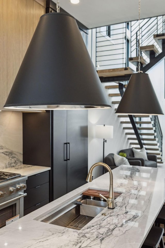 kitchen featuring light stone counters, stainless steel range, extractor fan, and sink