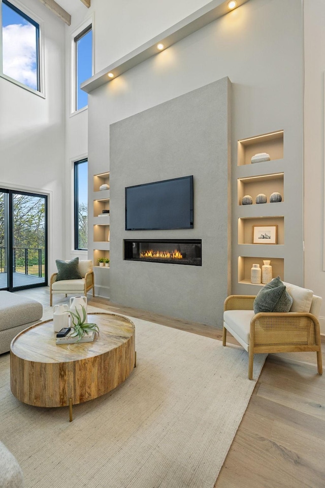 living room featuring hardwood / wood-style floors, a towering ceiling, and built in features