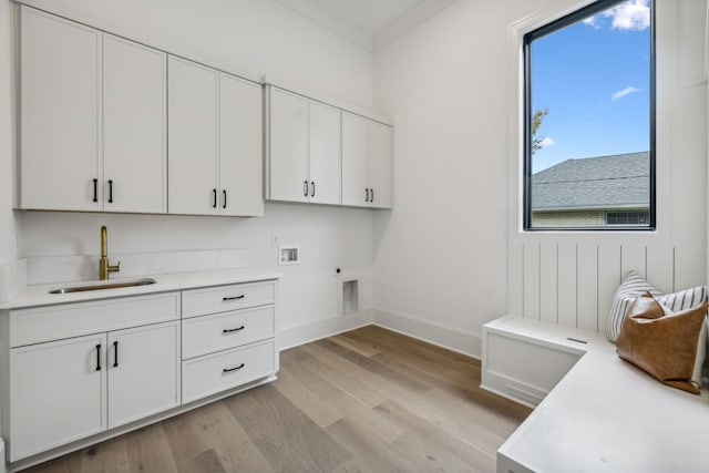 washroom featuring cabinets, hookup for a washing machine, ornamental molding, sink, and light hardwood / wood-style flooring