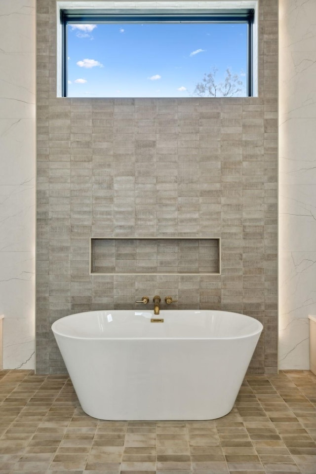 bathroom featuring tile walls, a wealth of natural light, and a tub