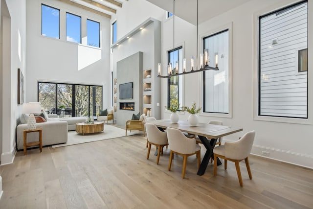 dining space with a towering ceiling and light hardwood / wood-style floors