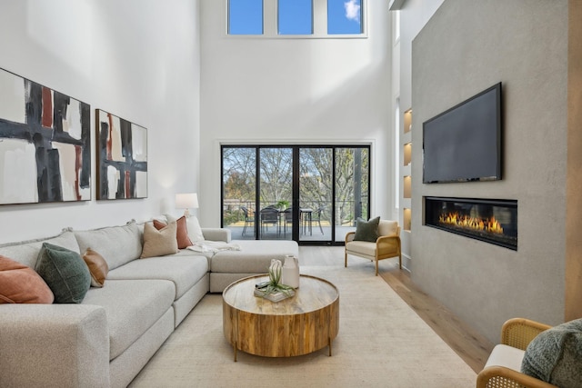 living room featuring a towering ceiling and light hardwood / wood-style floors