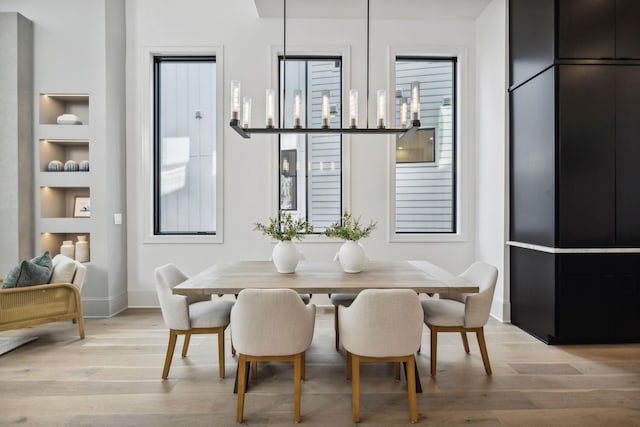 dining area with built in shelves and light hardwood / wood-style flooring