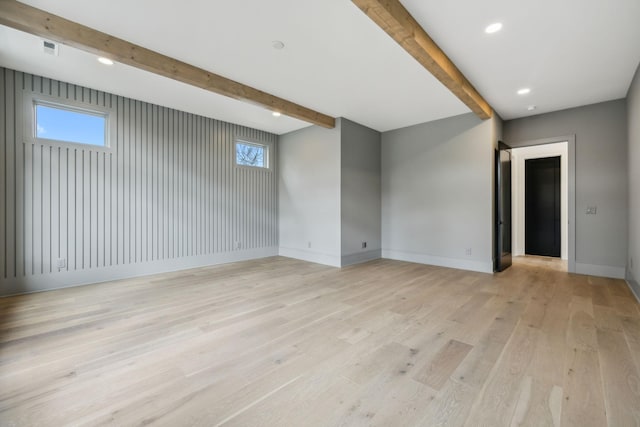 empty room with beamed ceiling and light wood-type flooring