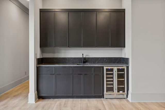 bar featuring sink, beverage cooler, and light hardwood / wood-style flooring