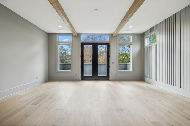 spare room featuring beamed ceiling, french doors, and light hardwood / wood-style flooring