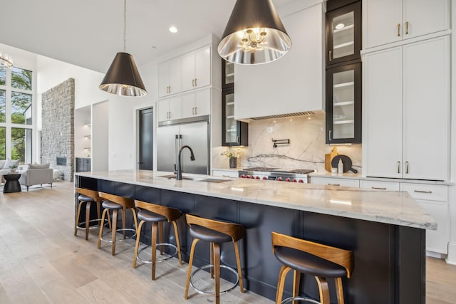 kitchen with built in fridge, decorative backsplash, a kitchen bar, and white cabinetry