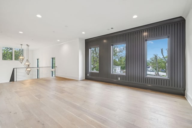 spare room with light hardwood / wood-style flooring, a healthy amount of sunlight, and crown molding