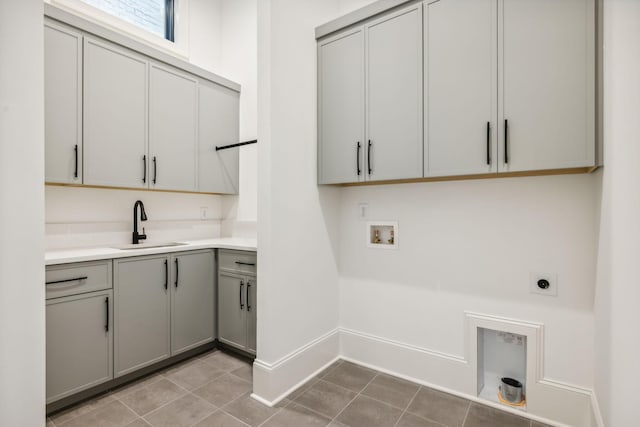 clothes washing area featuring cabinets, sink, hookup for a washing machine, light tile patterned floors, and hookup for an electric dryer