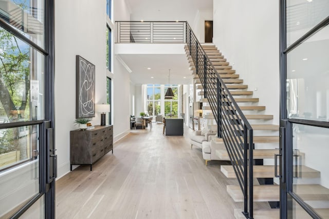 entryway featuring light wood-type flooring, a high ceiling, and french doors