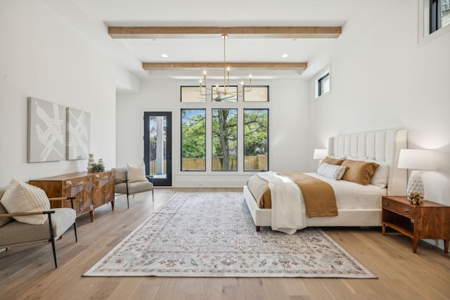 bedroom with a chandelier, beam ceiling, a towering ceiling, and light hardwood / wood-style floors