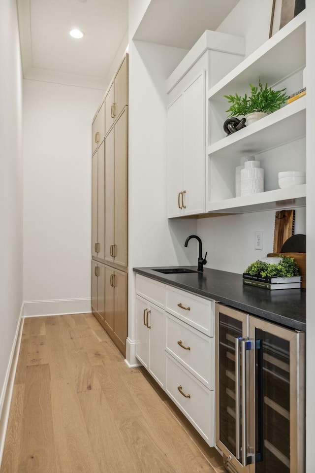 bar with wine cooler, white cabinetry, sink, and light hardwood / wood-style floors