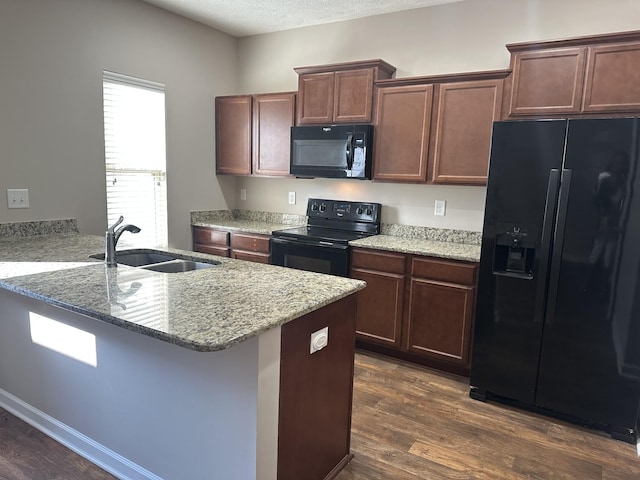 kitchen with sink, light stone countertops, black appliances, and dark hardwood / wood-style floors