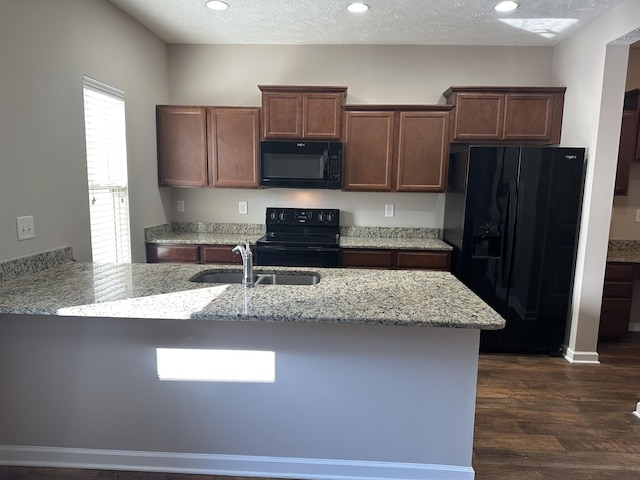 kitchen with light stone counters, a textured ceiling, dark hardwood / wood-style floors, black appliances, and sink