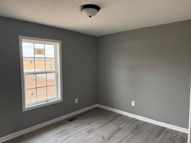 unfurnished room with plenty of natural light, wood-type flooring, and a textured ceiling