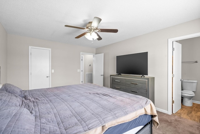 carpeted bedroom with a textured ceiling, ensuite bath, and ceiling fan