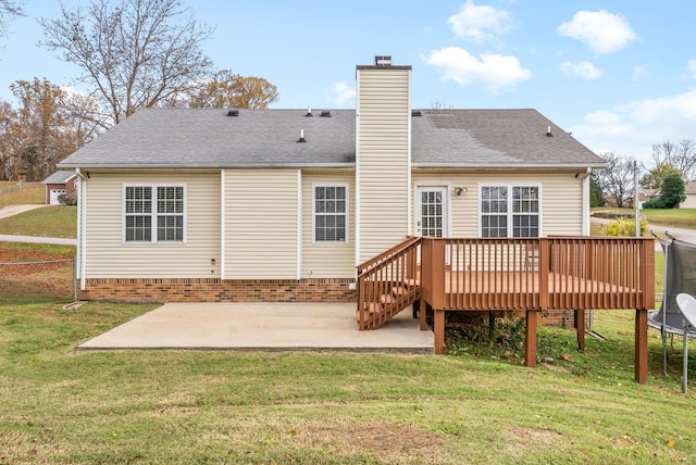 back of house featuring a lawn, a patio, a deck, and a trampoline