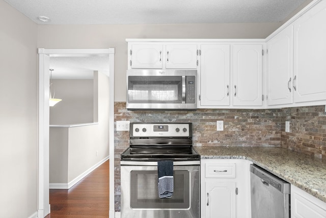 kitchen with white cabinetry, dark wood-type flooring, stainless steel appliances, light stone counters, and backsplash