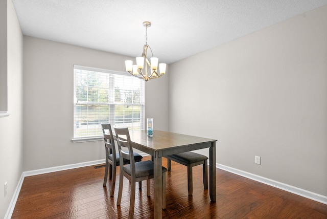 dining area with a chandelier, a textured ceiling, and dark hardwood / wood-style floors