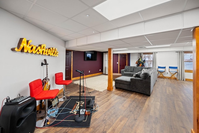 living room featuring wood-type flooring and a drop ceiling