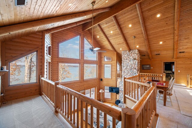 corridor featuring beam ceiling, wood ceiling, light carpet, and wooden walls