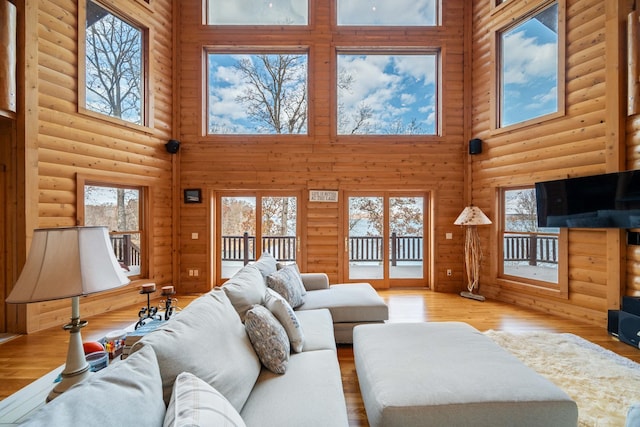 living room with a towering ceiling, a wealth of natural light, and light hardwood / wood-style flooring