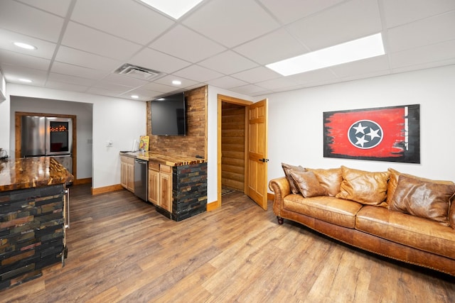 living room featuring hardwood / wood-style flooring, a drop ceiling, and bar area