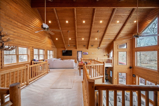 interior space with beam ceiling, wooden walls, high vaulted ceiling, and wooden ceiling