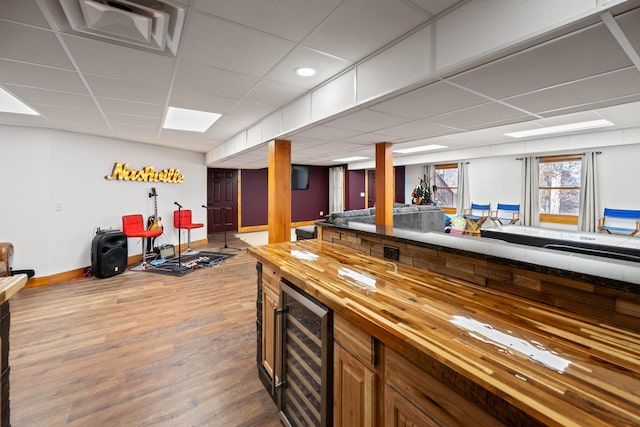 bar featuring wood counters, a paneled ceiling, hardwood / wood-style flooring, and wine cooler