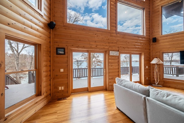 living room featuring a healthy amount of sunlight, a high ceiling, and light hardwood / wood-style flooring