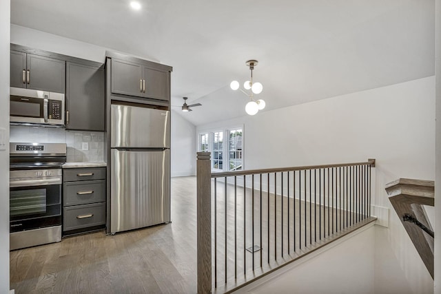 kitchen with ceiling fan, stainless steel appliances, light hardwood / wood-style floors, lofted ceiling, and decorative backsplash